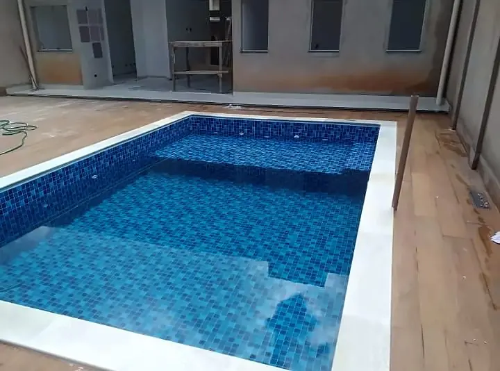 Piscina de vinil recém-instalada em pátio de casa, com piso de madeira e borda clara
